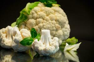 slices of raw small raw cauliflower on black background photo