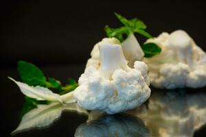 slices of raw small raw cauliflower on black background photo