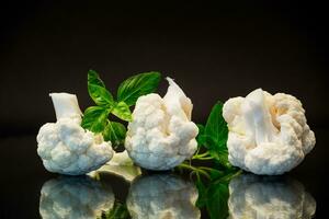 slices of raw small raw cauliflower on black background photo