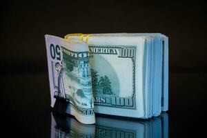 stack of dollar bills collected in an elastic band and a stationery clip photo