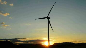 vent turbine énergie renouvelable en mouvement à champ à le coucher du soleil video