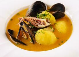 Creamy seafood soup with mussels, potatoes and small octopus photo