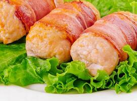 Pork cutlets wrapped in bacon on white photo