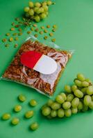 packaged raisins and grapes on green background photo