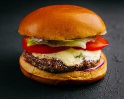 delicioso hamburguesa con queso en un negro antecedentes foto