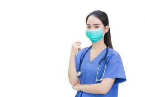 Professional young Asian woman doctor wears medical clothing and medical face mask to protect Coronavirus disease 2019 Covid 19 outbreak while shows her hand to suggest something on white background. photo
