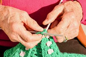 an older woman is knitting a green crocheted bag photo