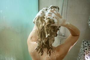 espalda ver de mujer tomando un ducha en baño foto
