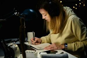 Woman working from home workplace at night, using laptop photo