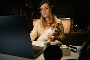 mujer y perro utilizando ordenador portátil a noche foto