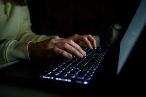 Anonymous woman working on laptop at night photo