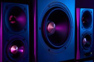 Two sound speakers and subwoofer on dark background with neon lights photo