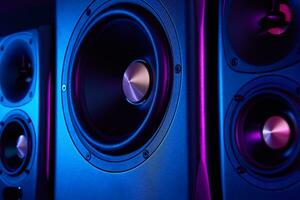 Two sound speakers and subwoofer on dark background with neon lights photo