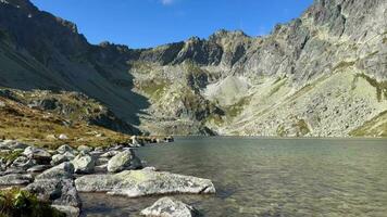 Lake Hincovo pleso in a canyon on top of a mountain in Slovakia on a clear sunny day. video