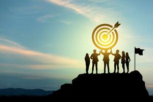 Goal setting towards planning for the future. Silhouettes of group businessmen holding target boards with flags planted on a mountain. Concept of a clear planning process and teamwork. photo