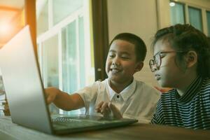 asian children learning on line with computer laptop at home living room photo