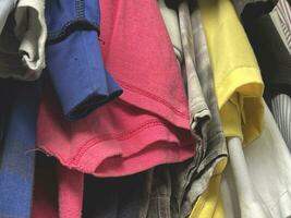 stack of different colorful clothes in a closet photo