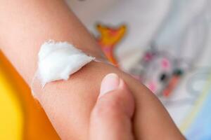 Close up of mother holding hand's girl with plaster are placed on the child's arm after vaccination. photo