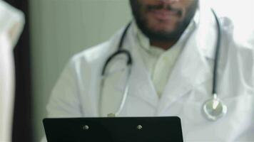 A doctor holds a paper holder and writes video