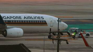 PHUKET, THAILAND FEBRUARY 27, 2023 Shot, Boeing 737 of Singapore Airlines at Phuket airport. Tractor towing a passenger plane. View of the apron from the terminal window video