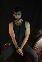 a man sitting on a leather chair with a cigarette photo