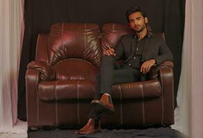 a man sitting on a brown leather couch photo