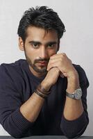 a man with a beard and a watch is sitting at a table photo