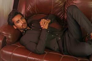 a man sitting on a brown leather couch photo