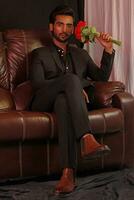 a man sitting on a brown leather couch photo