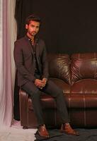 a man sitting on a brown leather couch photo