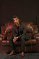 a man sitting on a brown leather couch photo