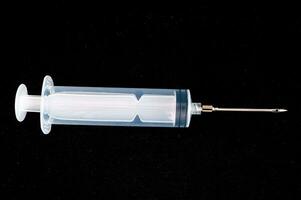 a syringe with a needle on a black surface photo