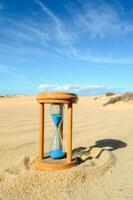 un reloj de arena en el arena en un soleado día foto