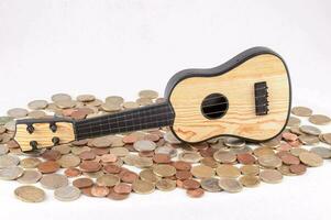 a small ukulele sits on top of a pile of coins photo