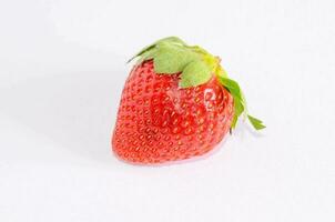 a single strawberry on a white surface photo