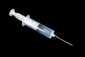 a syringe with a needle on a black surface photo