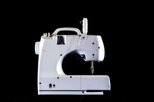 un blanco de coser máquina en un negro antecedentes foto