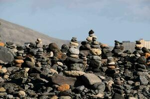 a pile of rocks on the beach with a city in the background photo