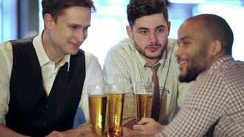 homme en portant une verre de Bière dans main tandis que séance à le bar video