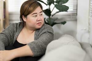 Sad Overweight plus size woman thinking about problems on sofa u photo