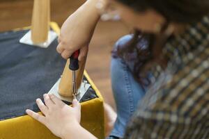 Asian Woman self repairs furniture renovation using equipment to diy repairing furniture sitting on the floor at home photo