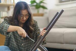 Asian Woman self repairs furniture renovation using equipment to diy repairing furniture sitting on the floor at home photo