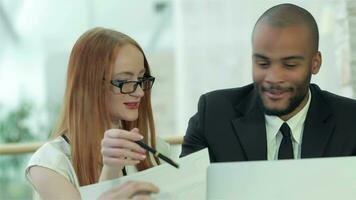 Smiling successful businessmen sitting at table in office while discussing video