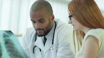 Smiling doctor talking to patient while sitting at a table in the hospital video