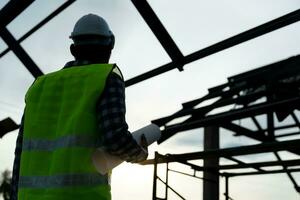 inspector or engineer is inspecting construction and quality assurance new house using a blue print. Engineer or architects or contactor work to build the house before handing it over to the homeowner photo