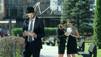 Successful businessman with tablet stands on the background of two businesswomen video