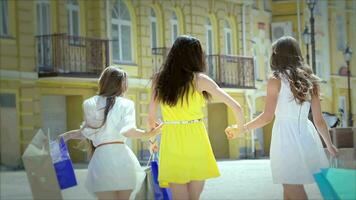 Three cute girls walking hand in hand while shopping video