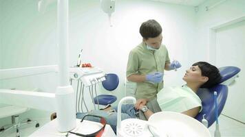 tandläkare kommer till de patient i de stol och börjar till inspektera tänder video