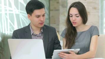 Young business man and woman discussing collating data on the tablet video