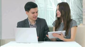 Attractive business man and woman discussing collating data on the tablet video